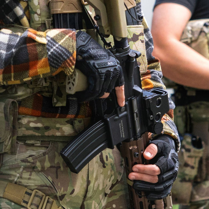 Operator wearing MPF-55 M-Pact gloves demonstrating trigger discipline with AR rifle in tactical environment
