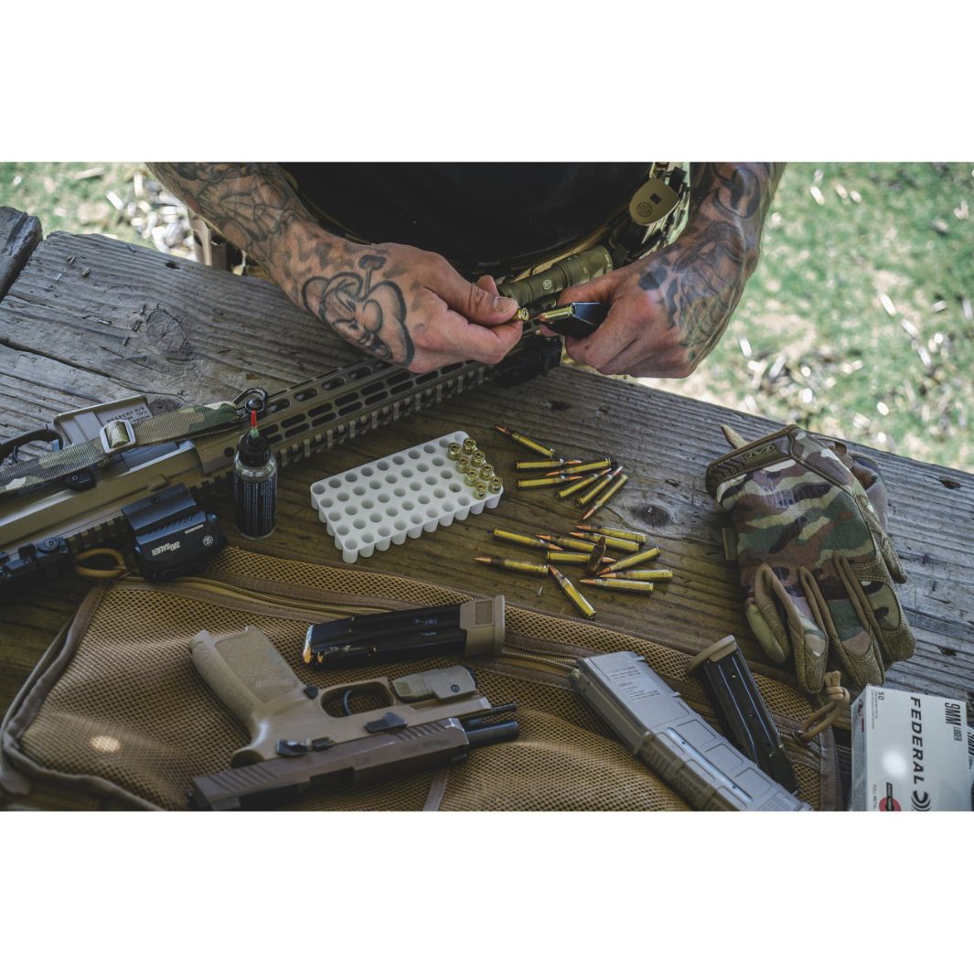 Mechanix Multicam Gloves placed on shooting bench next to tactical rifle, mags, and ammo