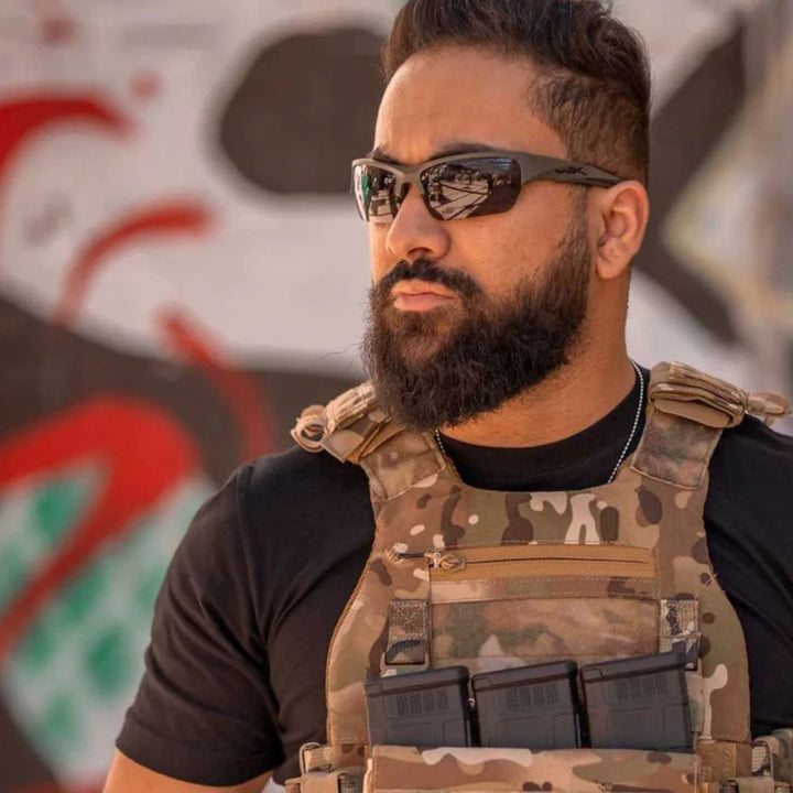 Man wearing Wiley X Valor ballistic sunglasses with Grey lenses and tactical vest in an outdoor setting.